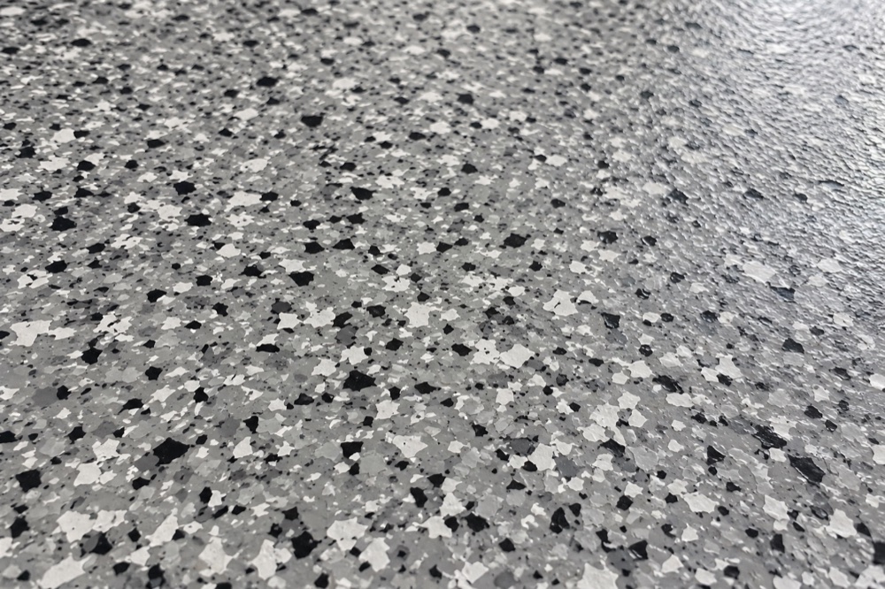 Close-up of a graphite, grey and white decorative epoxy flake surface